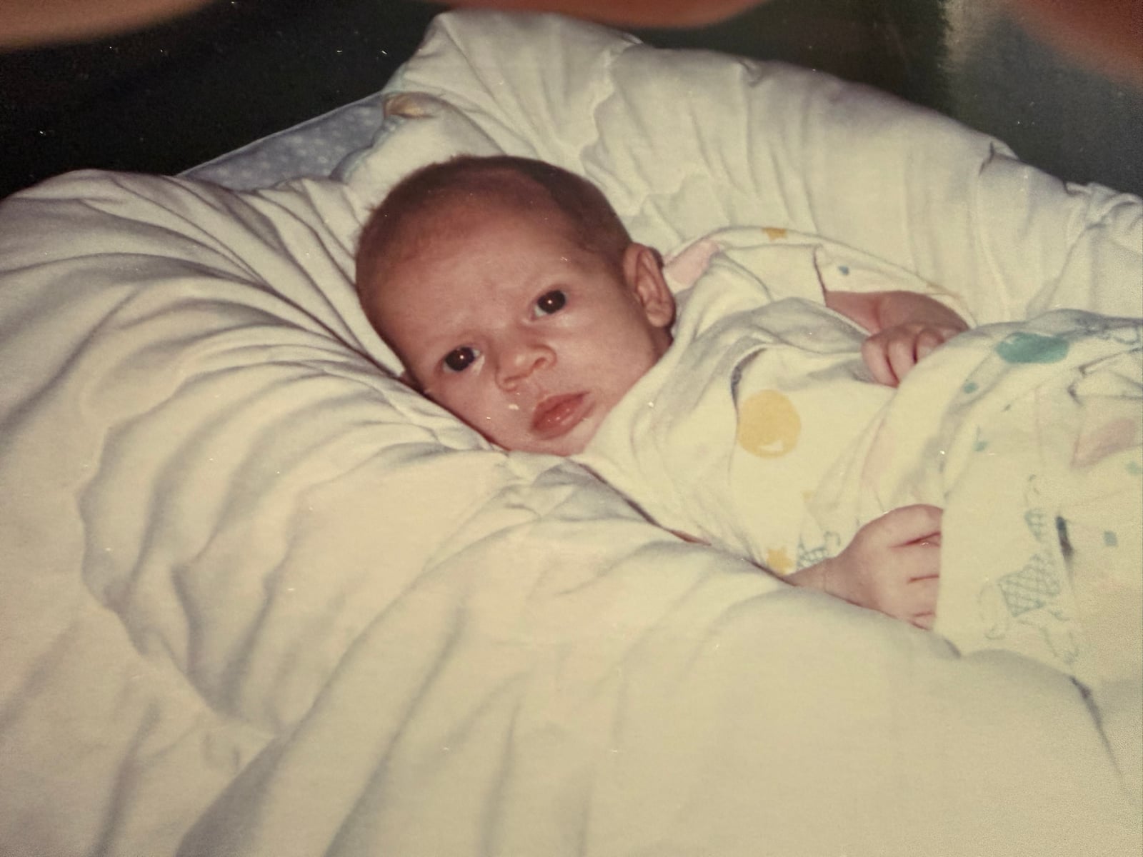 Baby KT bundled up in a blanket, giving the camera a serious look